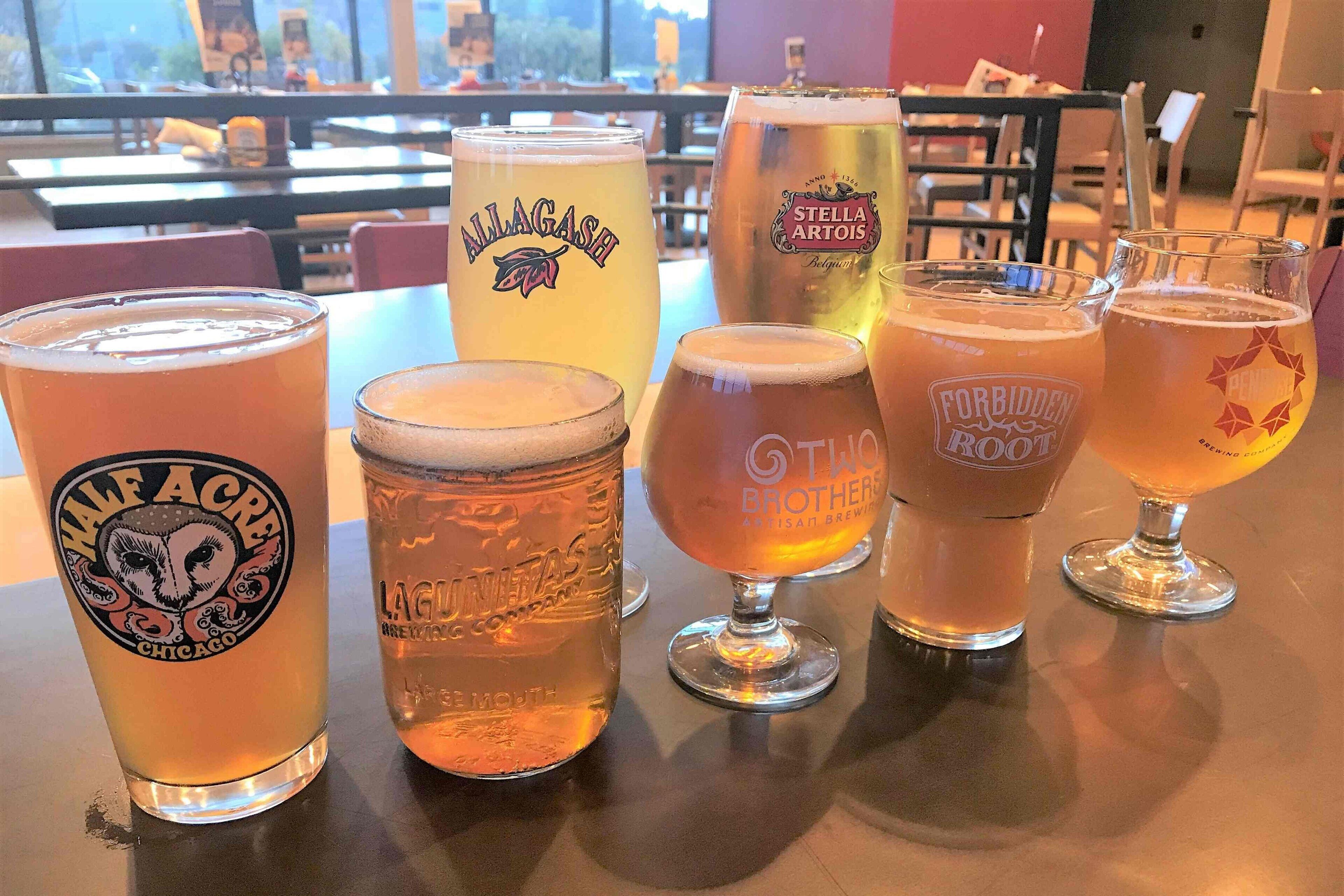 Variedad de vasos de cerveza sobre una mesa en un restaurante.