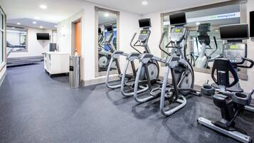 A gym with multiple treadmills, stationary bikes, and a mirrored wall.