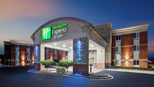 L’entrée d’un hôtel Holiday Inn Express & Suites, avec un pilier en pierre et des lumières bleues illuminées.