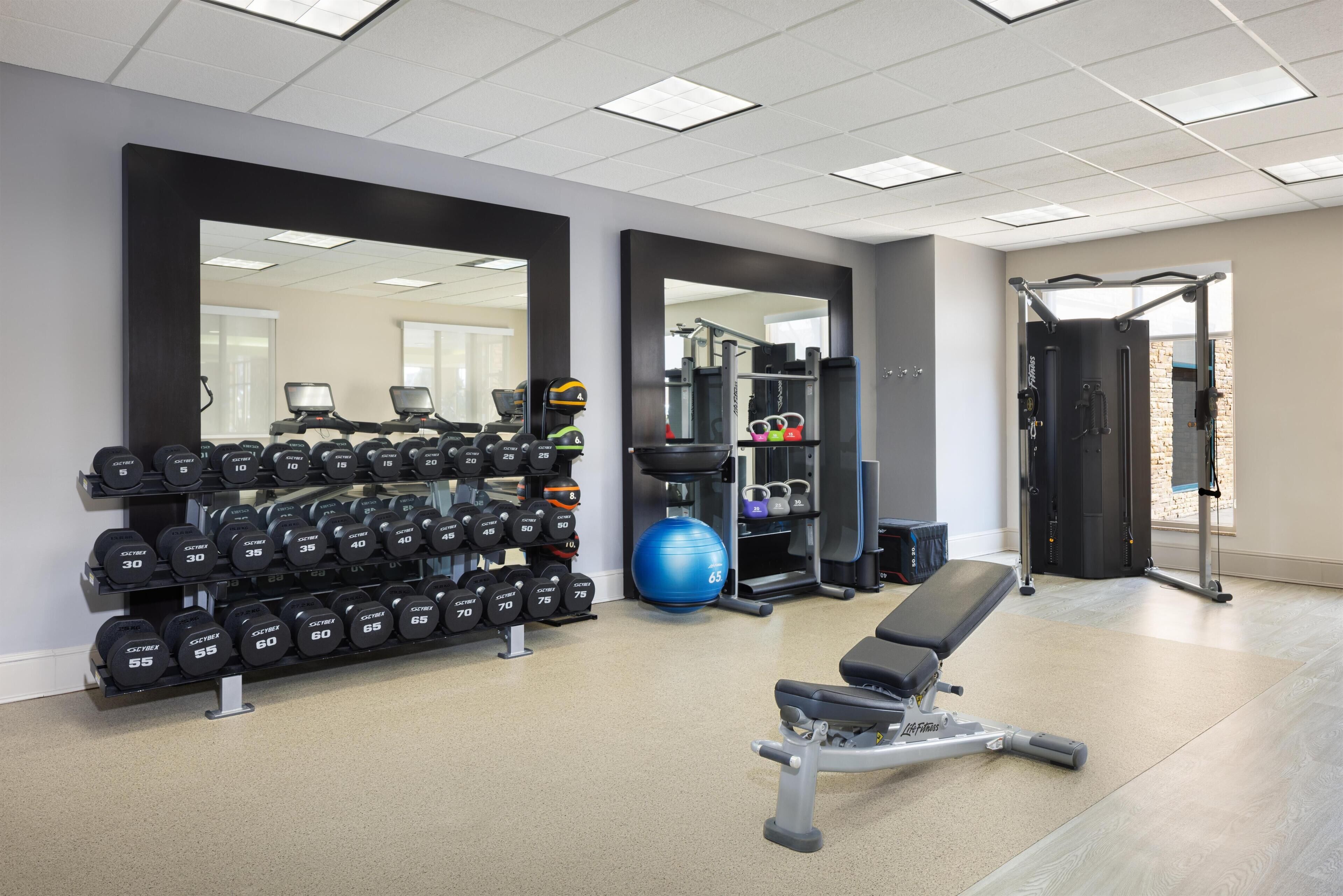 Een sportschool met gewichthefapparatuur, dumbbells en trainingsballen.