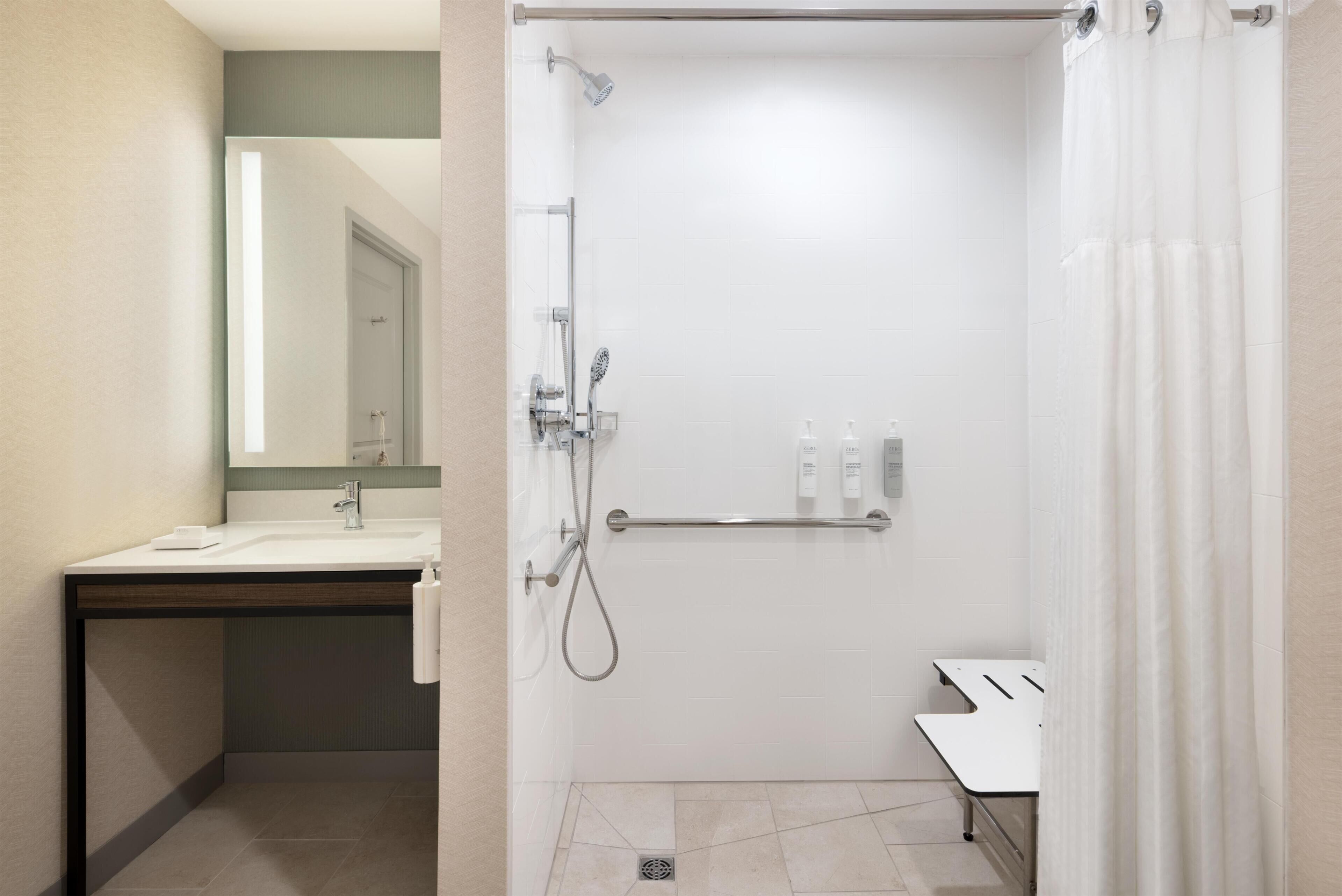 A modern bathroom with a shower, sink, and mirror.