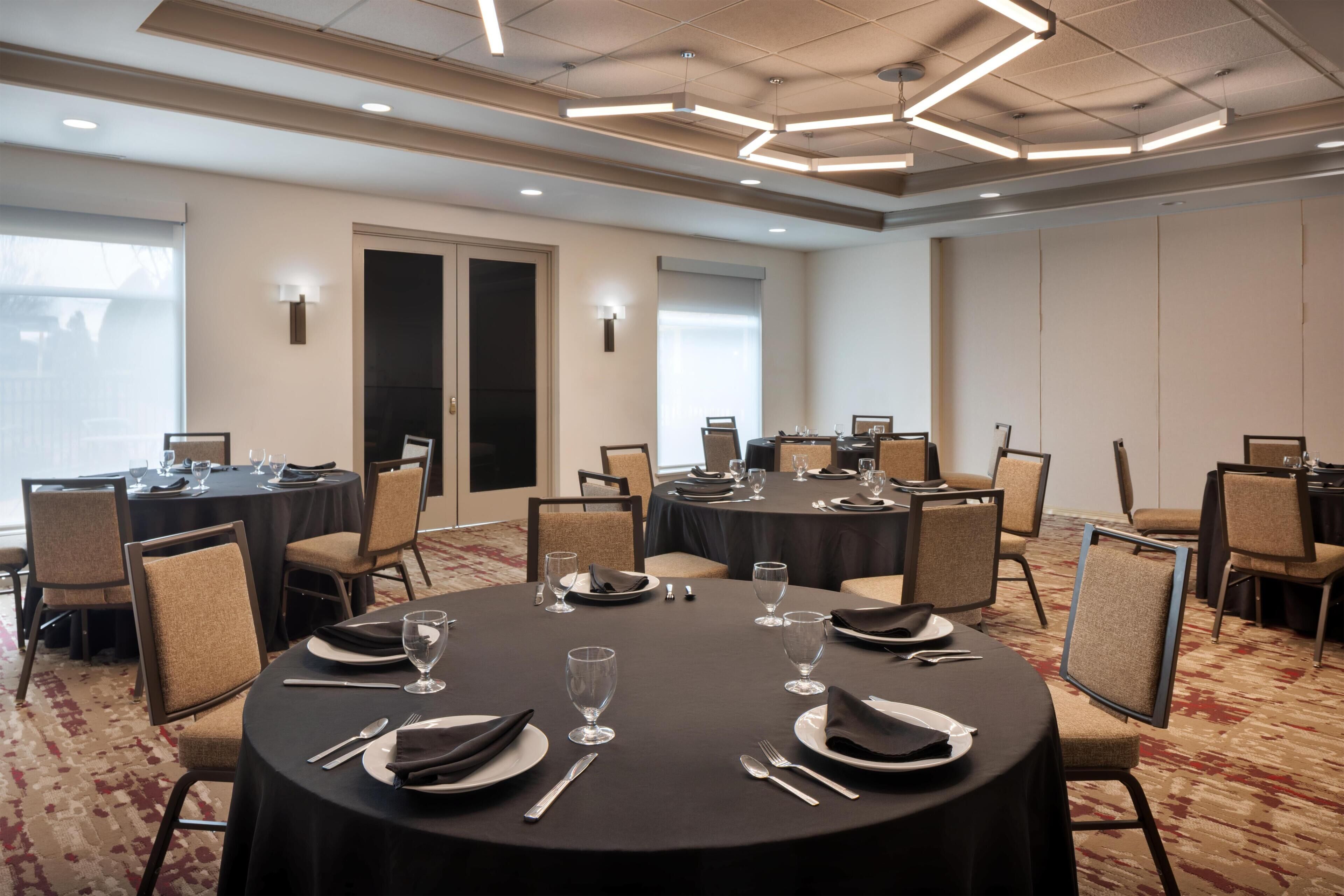 A conference room with round tables, chairs, and a carpeted floor.