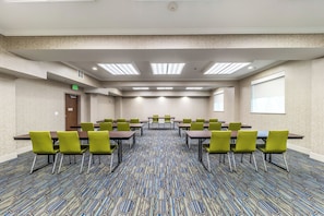 A conference room with tables and chairs, a patterned carpet, and a door with an exit sign. - Holiday Inn Express & Suites Fort Worth - Fossil Creek by IHG (Fort Worth)