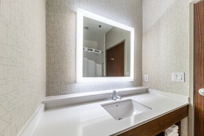 A bathroom with a white sink, a mirror, and a shower visible in the background. - Holiday Inn Express & Suites Fort Worth - Fossil Creek by IHG (Fort Worth)