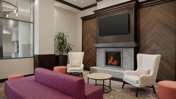 A modern lounge area with a fireplace, comfortable seating, and a large flat-screen TV mounted on the wall.