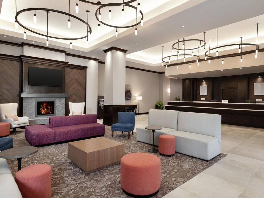 A modern lobby with a fireplace, sofas, and a reception desk.