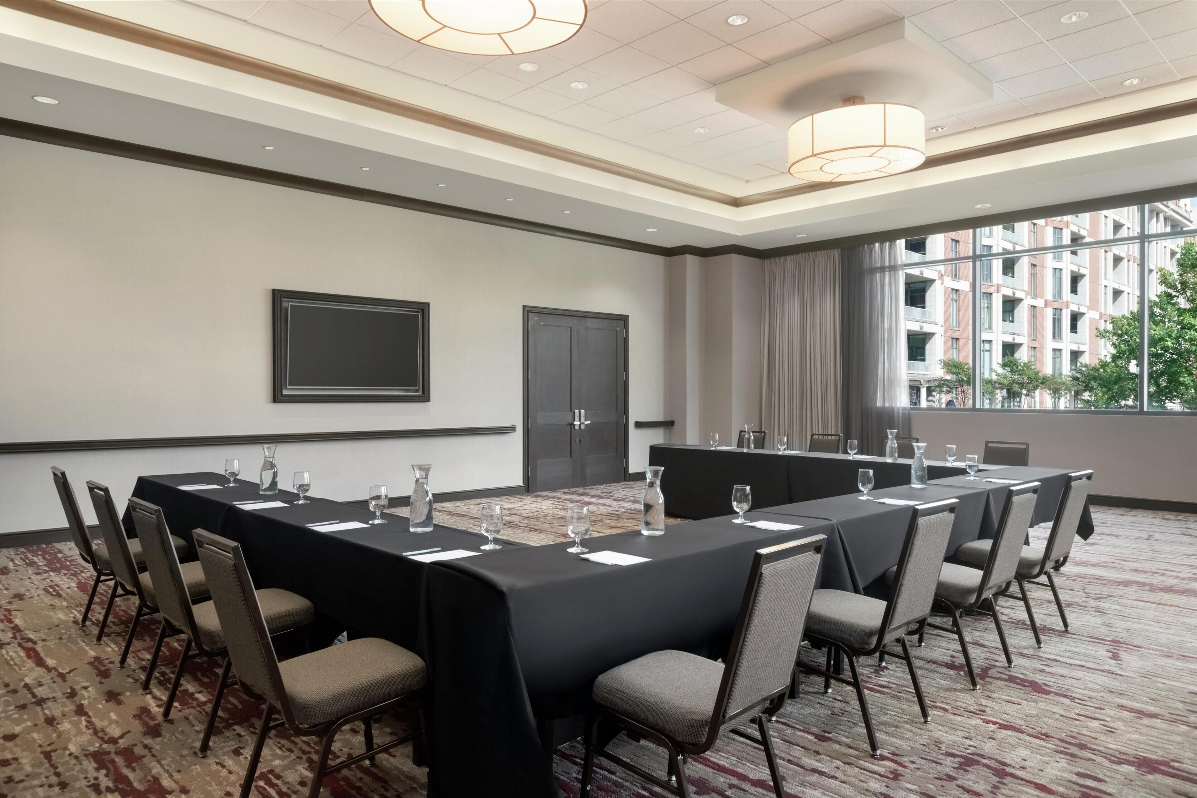A conference room with a long table, chairs, and a projector screen.