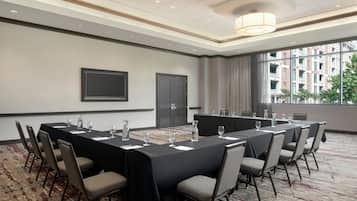 A conference room with a long table, chairs, and a projector screen.