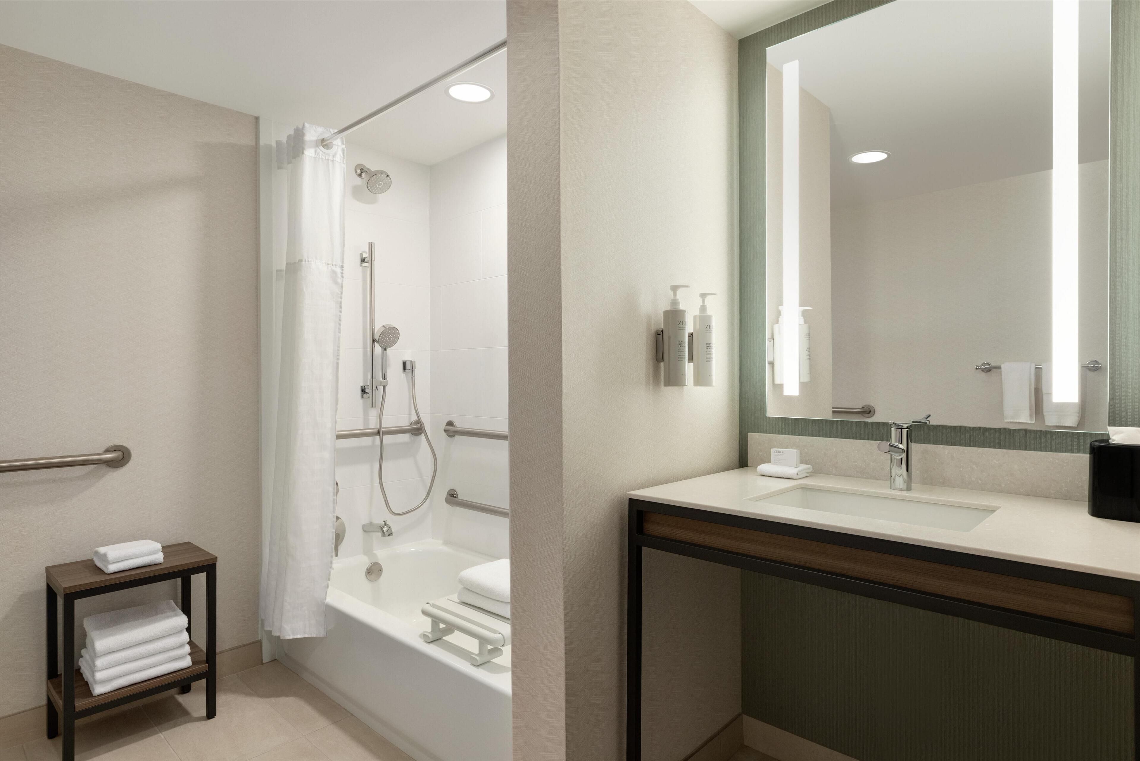 A modern bathroom with a shower, toilet, sink, and a mirror.