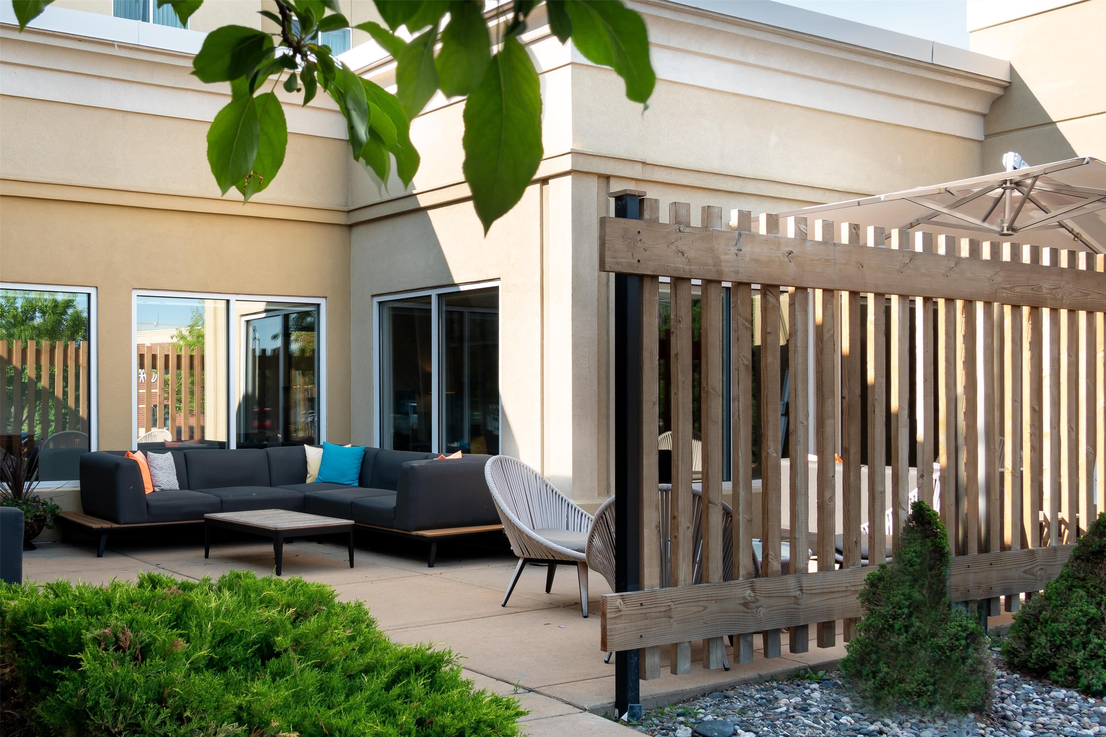 An outdoor patio area with a sofa, chairs, and a wooden fence.