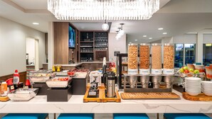 A modern breakfast bar with a chandelier, buffet with various food options, and seating areas. - Hilton Garden Inn Billings (Billings)