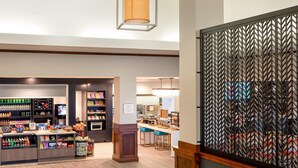 A spacious lobby with hexagonal pendant lights, a food kiosk, and a patterned wall. - Hilton Garden Inn Billings (Billings)