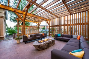 An outdoor patio with wooden pergola, seating area, and a fire feature. - Hilton Garden Inn Billings (Billings)
