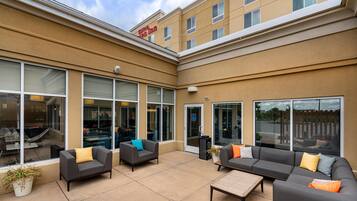 A hotel courtyard with outdoor seating, large windows, and a sign above the entrance.