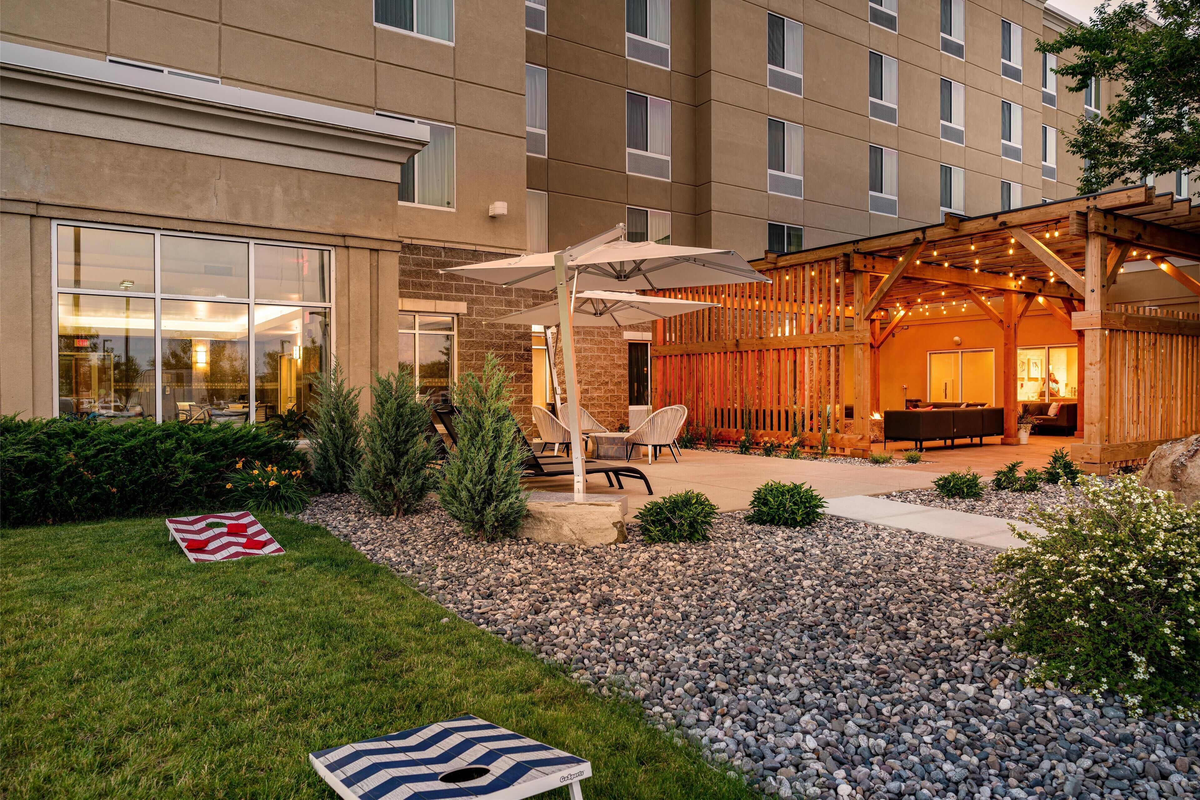 Une cour d’hôtel avec des espaces de détente en plein air, une terrasse couverte et un jardin bien entretenu.