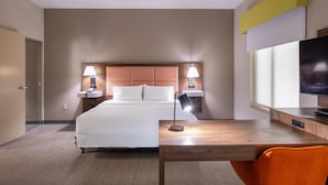 A hotel room with a large bed, two bedside lamps, a desk with a chair, and a TV.