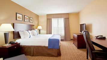 A hotel room with a large bed, two bedside lamps, a desk with a telephone, and a television.