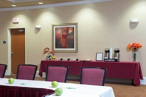 A conference room with a table set for a meeting, chairs, a coffee station, and an exit sign.