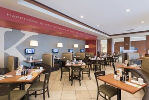 A hotel dining area with booths and tables, equipped with televisions, and a motivational quote on the wall.