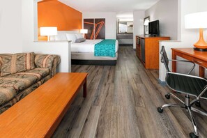 Une chambre d’hôtel comprenant un lit, un canapé, un bureau, une chaise, une télévision et une salle de bain.
