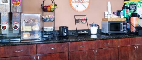 A kitchen counter with a coffee machine, a microwave, and a refrigerator.
