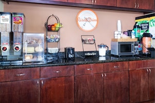 Uma bancada de cozinha com cafeteira, micro-ondas e geladeira.