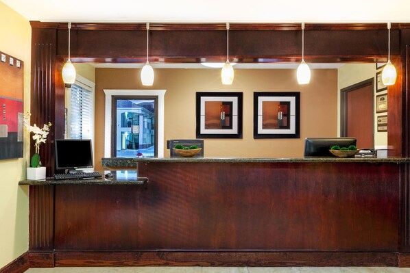 A reception desk with a dark wood finish, a computer, and framed pictures on the wall.