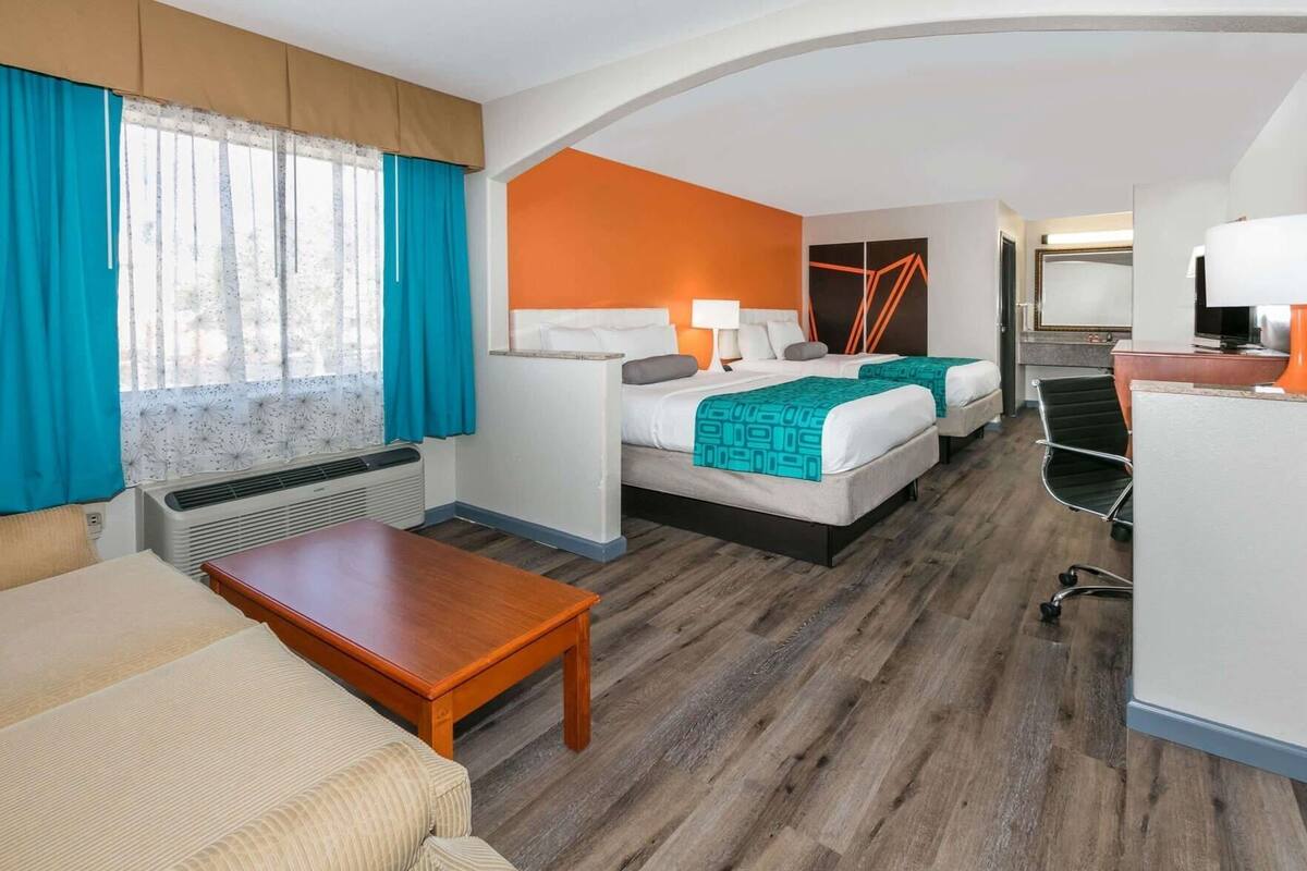 A hotel room with a bed, a desk, a chair, and a window with curtains.