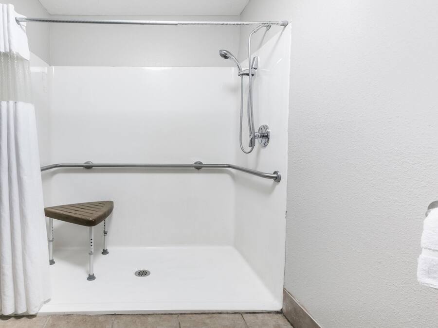 A walk-in shower with a bench, grab bars, and a showerhead.