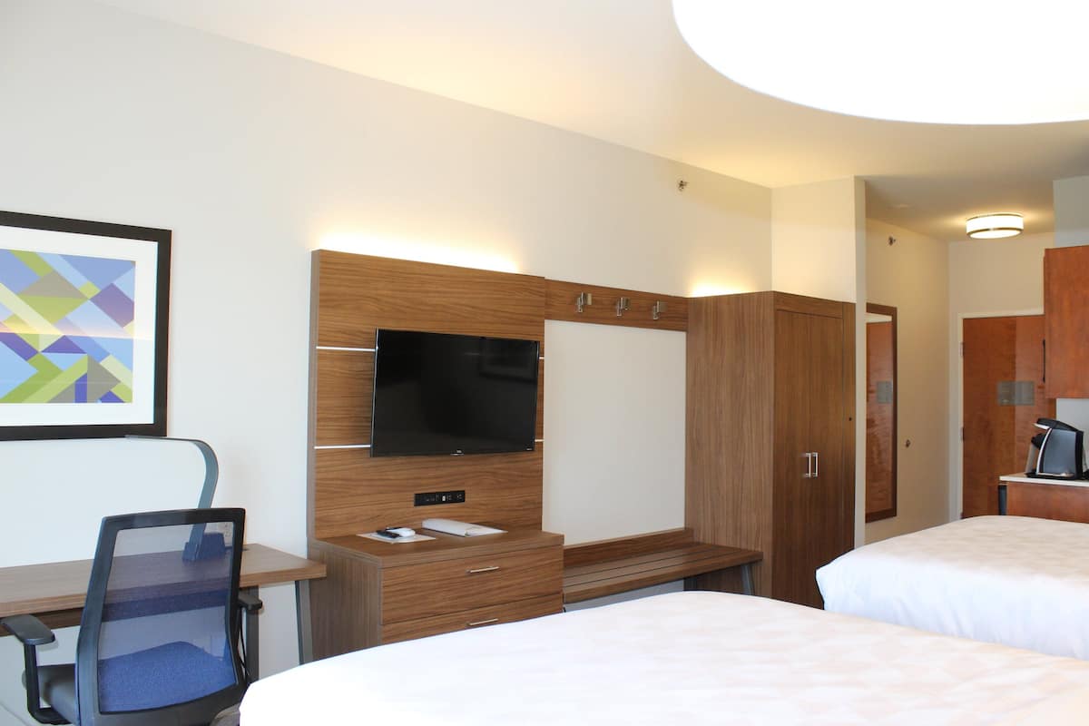 Hotellihuone, jossa on sänky, työpöytä tuolilla, televisio ja vaatekaappi.