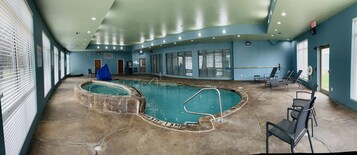 Una piscina interior con una profundidad de 15 metros, rodeada de zonas de estar y una pared azul.