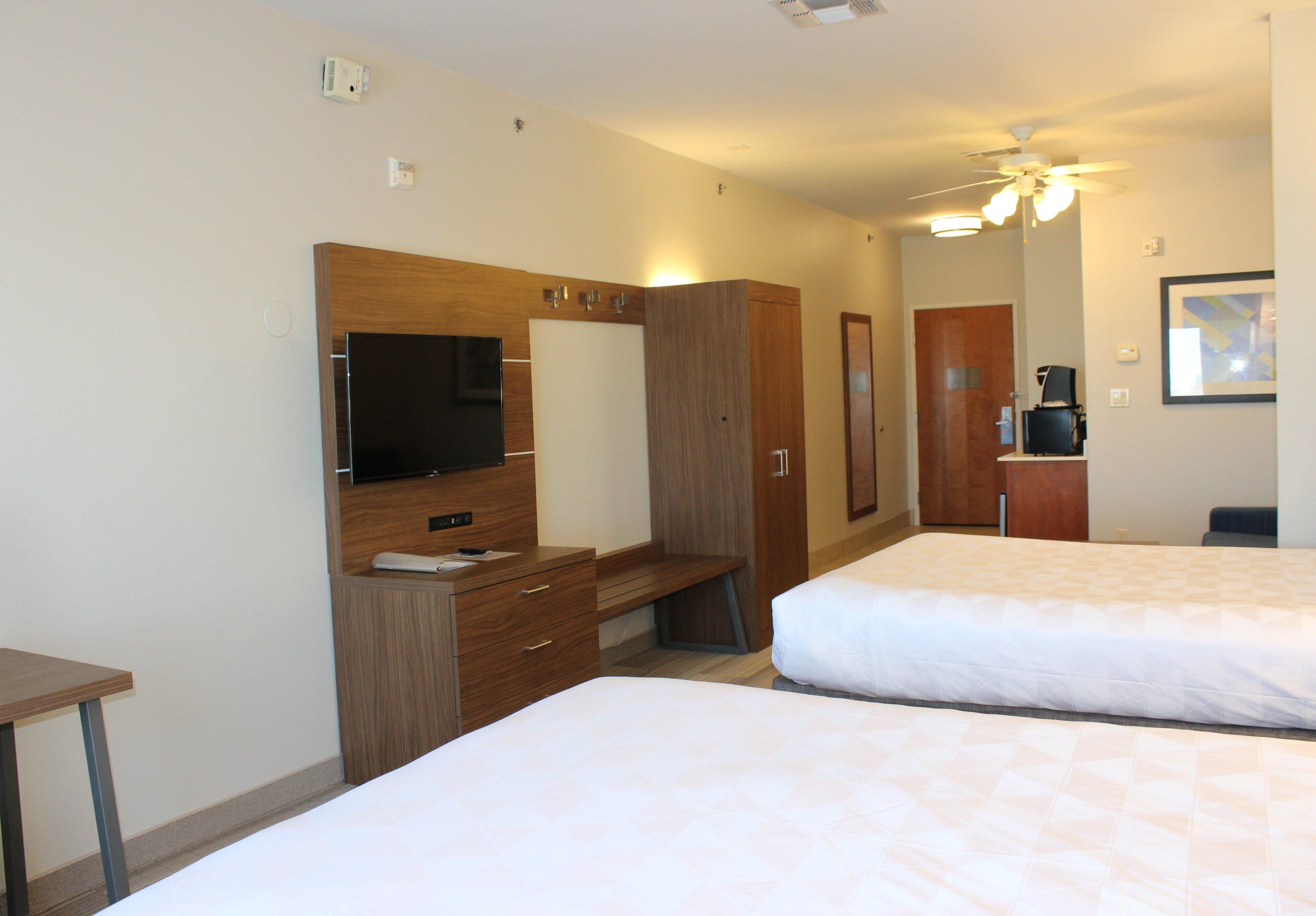 Habitación de hotel con cama, televisor, escritorio y armario.