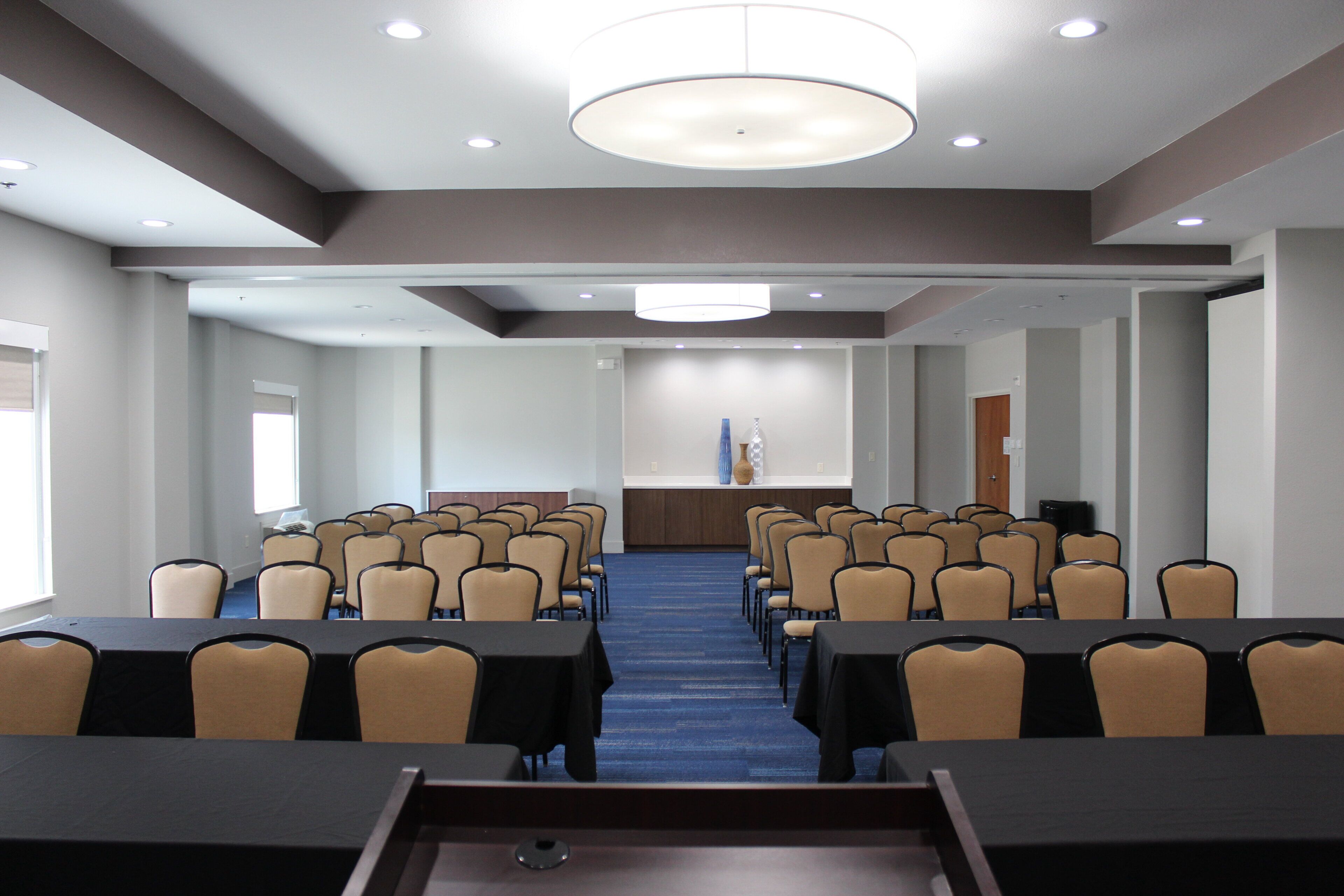 A conference room with rows of tables and chairs, a podium, and a flag.