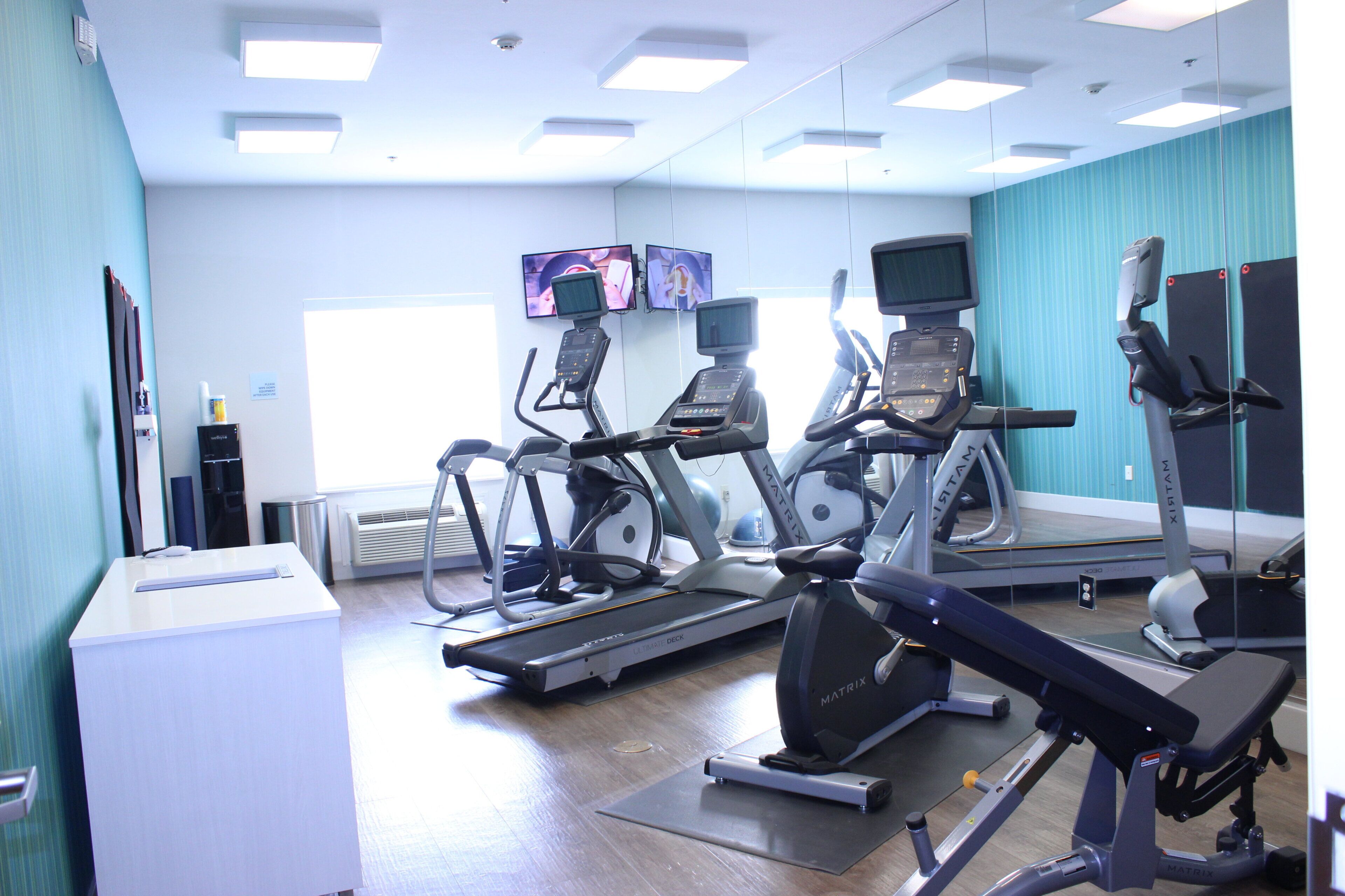 Un gimnasio con cintas de correr, elípticas y bicicletas estáticas.