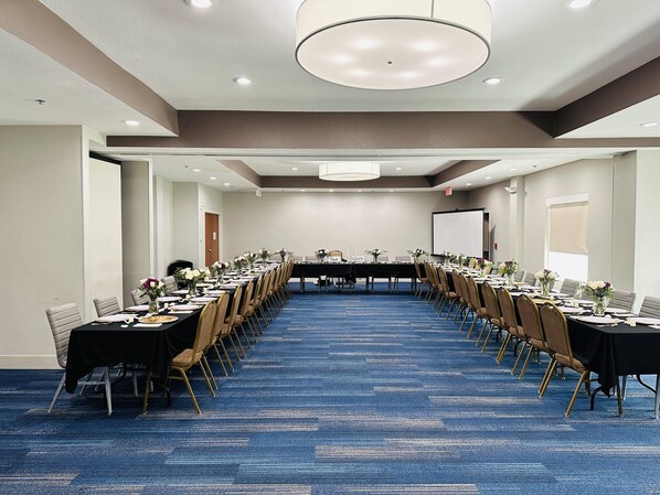 A conference room with long tables, chairs, and a projector screen. - Holiday Inn Express & Suites Mansfield by IHG (Mansfield)