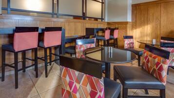 A restaurant with booths and high tables, wooden paneling, and tiled flooring.