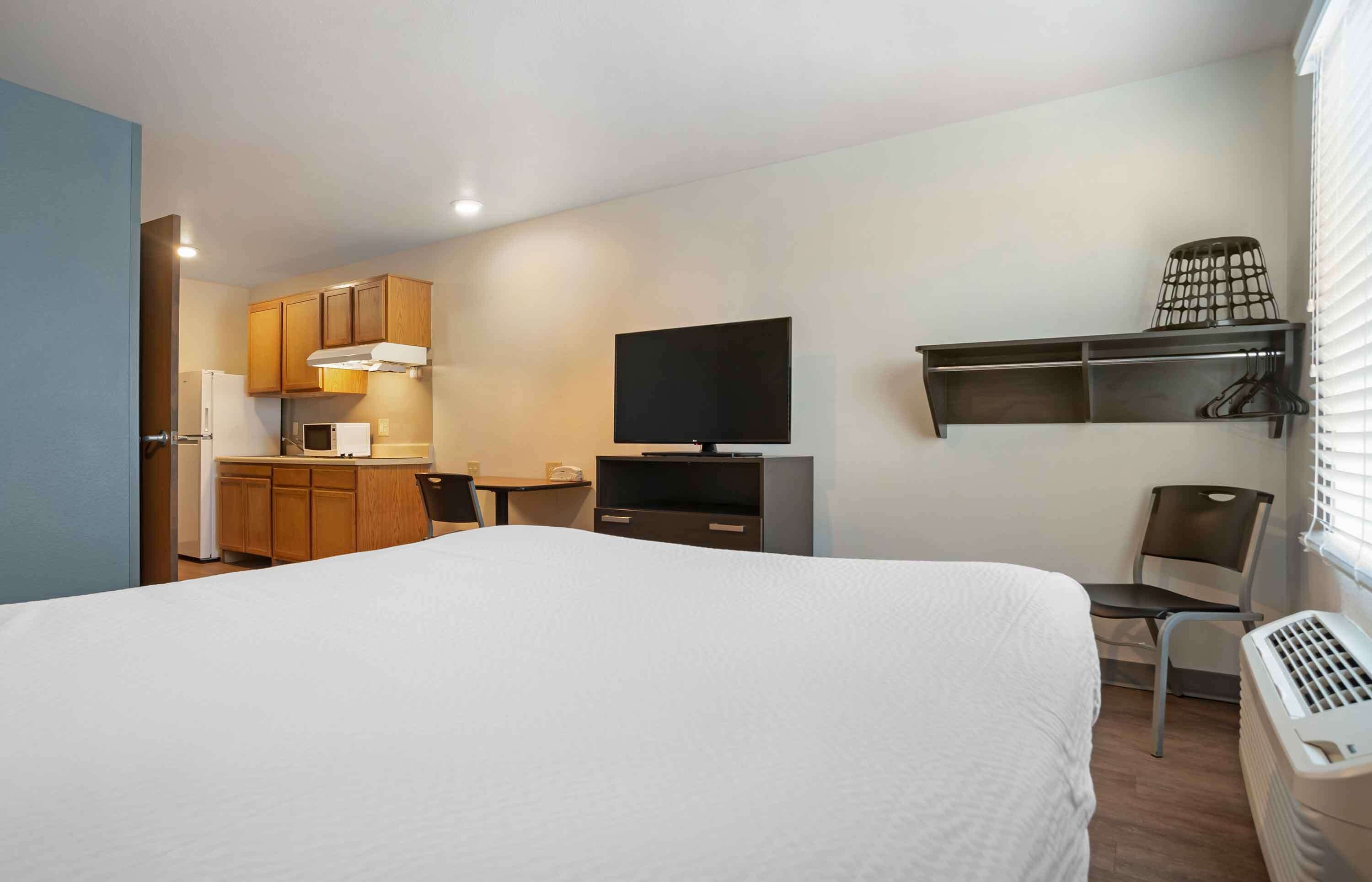 Une chambre d’hôtel équipée d’un lit, d’une télévision, d’une kitchenette et d’une chaise.