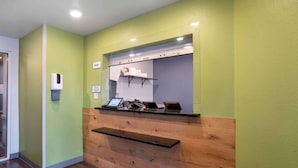 A reception area with a wooden counter, a hand sanitizer dispenser, and a sign indicating the office.