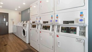 A laundry facility with multiple machines, each marked with a number and equipped with a digital display and payment card reader.