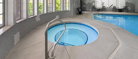An indoor swimming pool with a clear view of the surrounding area, including windows and a seating area.