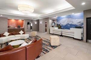 A modern lobby with a reception desk, seating area, and a large wall mural.
