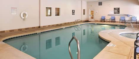 A swimming pool with a no diving sign, pool rules poster, and a lifebuoy.
