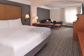 A hotel room with a large bed, a desk, a chair, a sofa, and a television. - La Quinta Inn & Suites by Wyndham Ruidoso Downs (Ruidoso Downs)