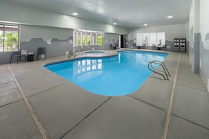 An indoor swimming pool with a clear blue water surface, surrounded by a tiled floor and walls.