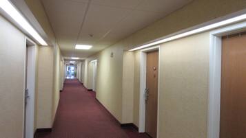 A long, narrow hotel corridor with carpeted floors and doors on both sides.