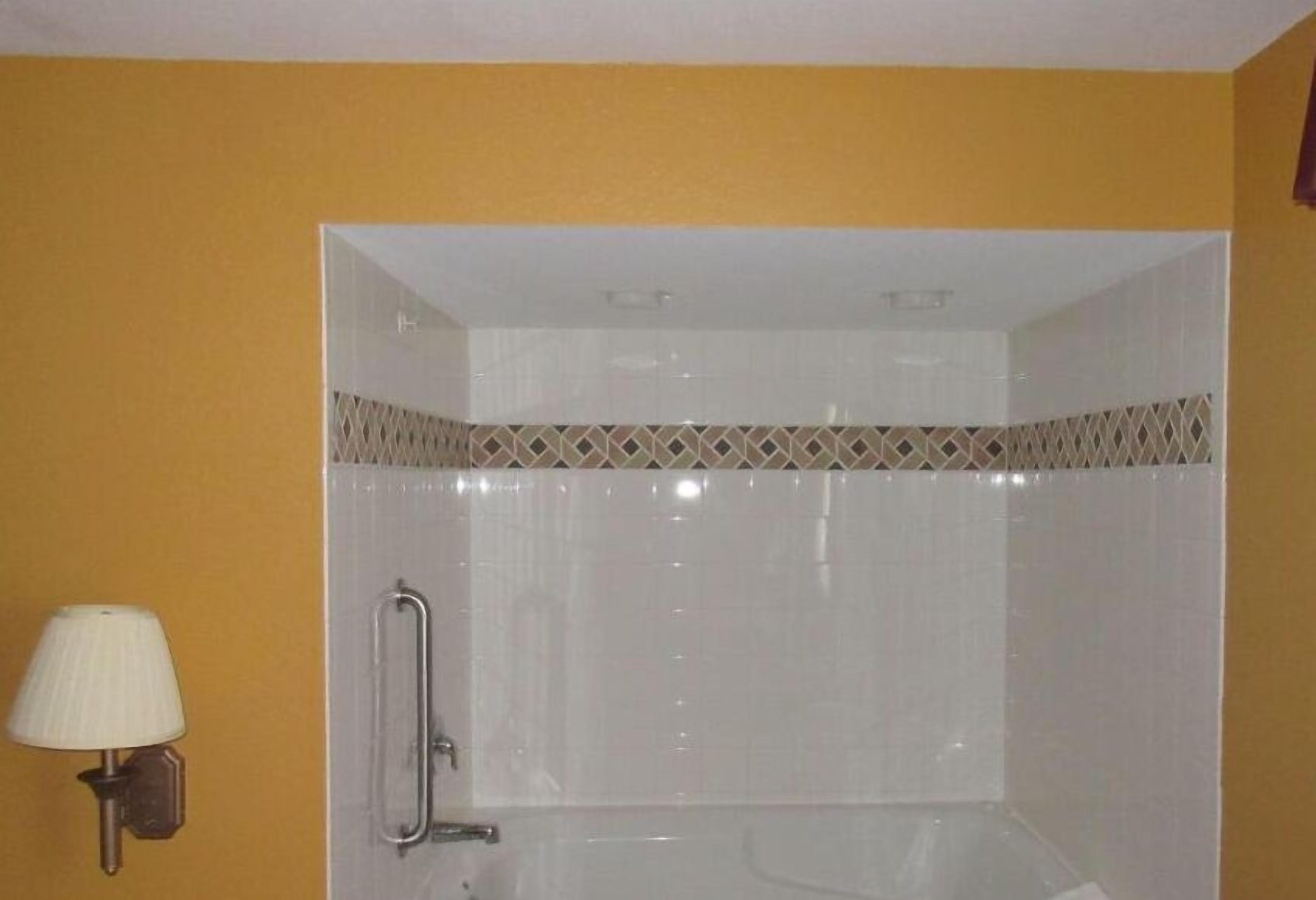 Un baño con ducha, un perchero para toallas y una lámpara en la pared.