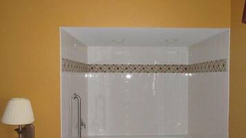 Un baño con ducha, un perchero para toallas y una lámpara en la pared.
