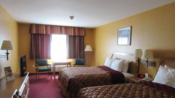 Une chambre d’hôtel avec deux lits, un bureau, une chaise et un téléviseur.
