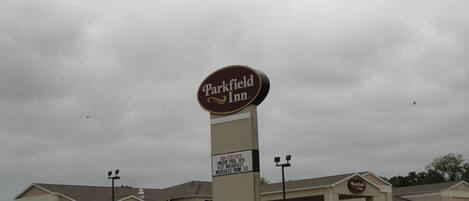 A Parkfield Inn hotel with a large sign, a parking lot, and a building with multiple windows.