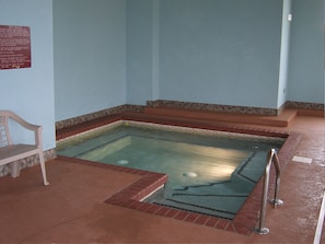 A spa area with a hot tub, a bench, and a sign with rules. - Parkfield Inn (Warsaw)